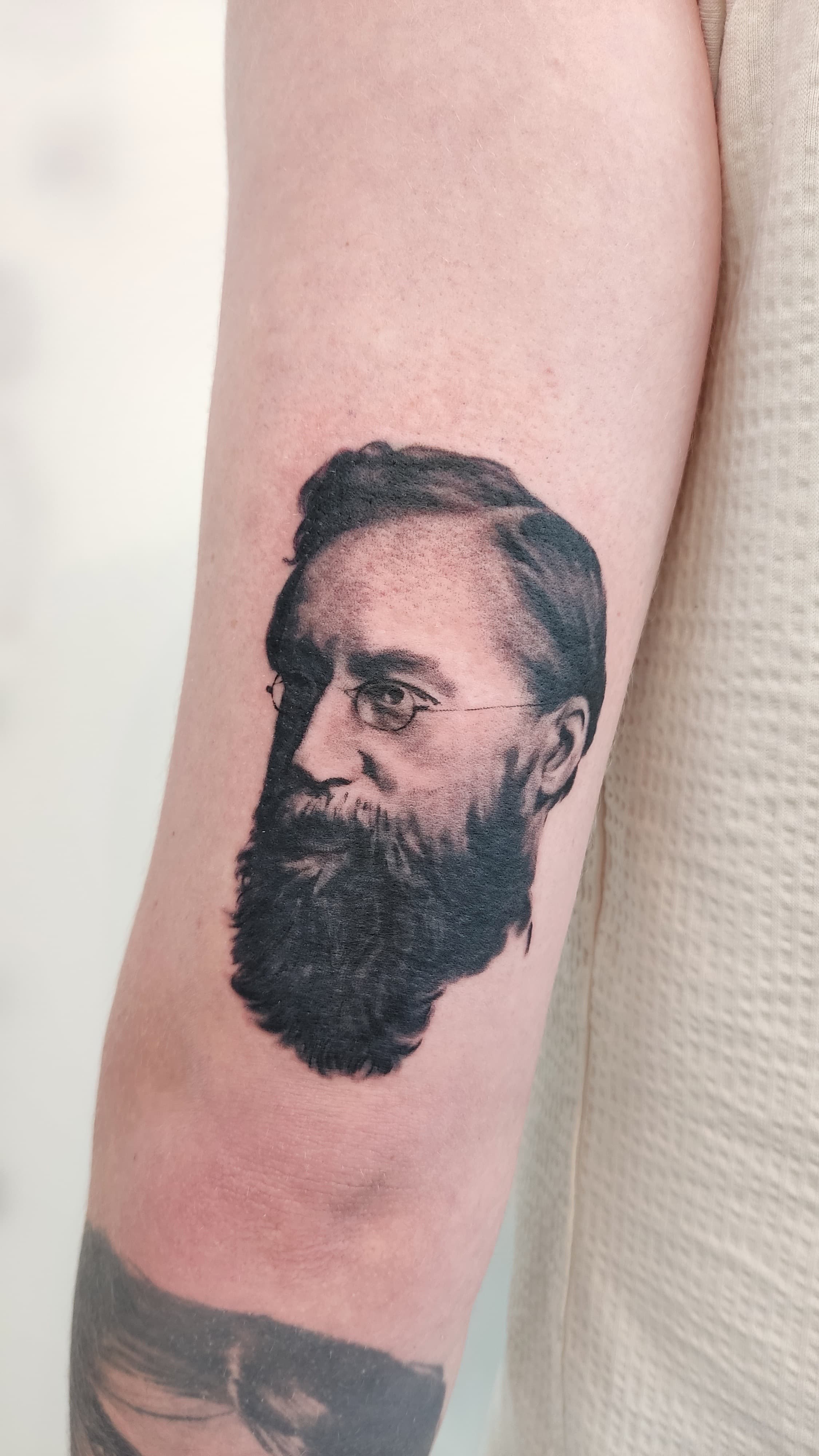 Bearded man portrait bicep tattoo in black and grey