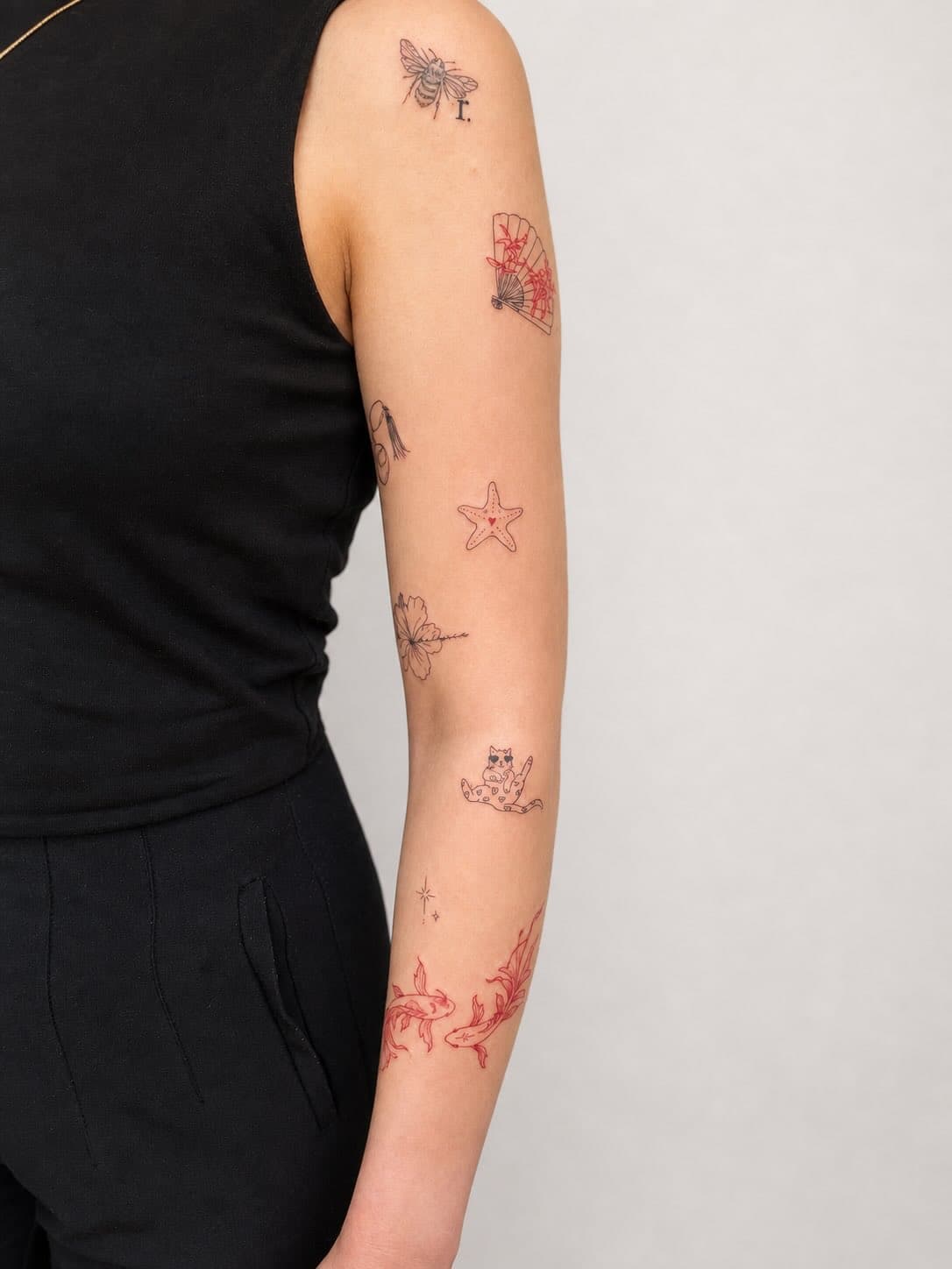 Fine line arm tattoos — bee, fan, starfish, cat, and koi