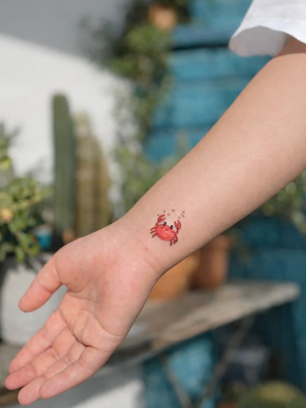 Minimal red crab wrist tattoo